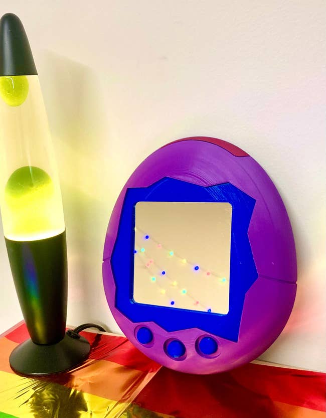 a mirror in the shape of a purple Tamagotchi toy