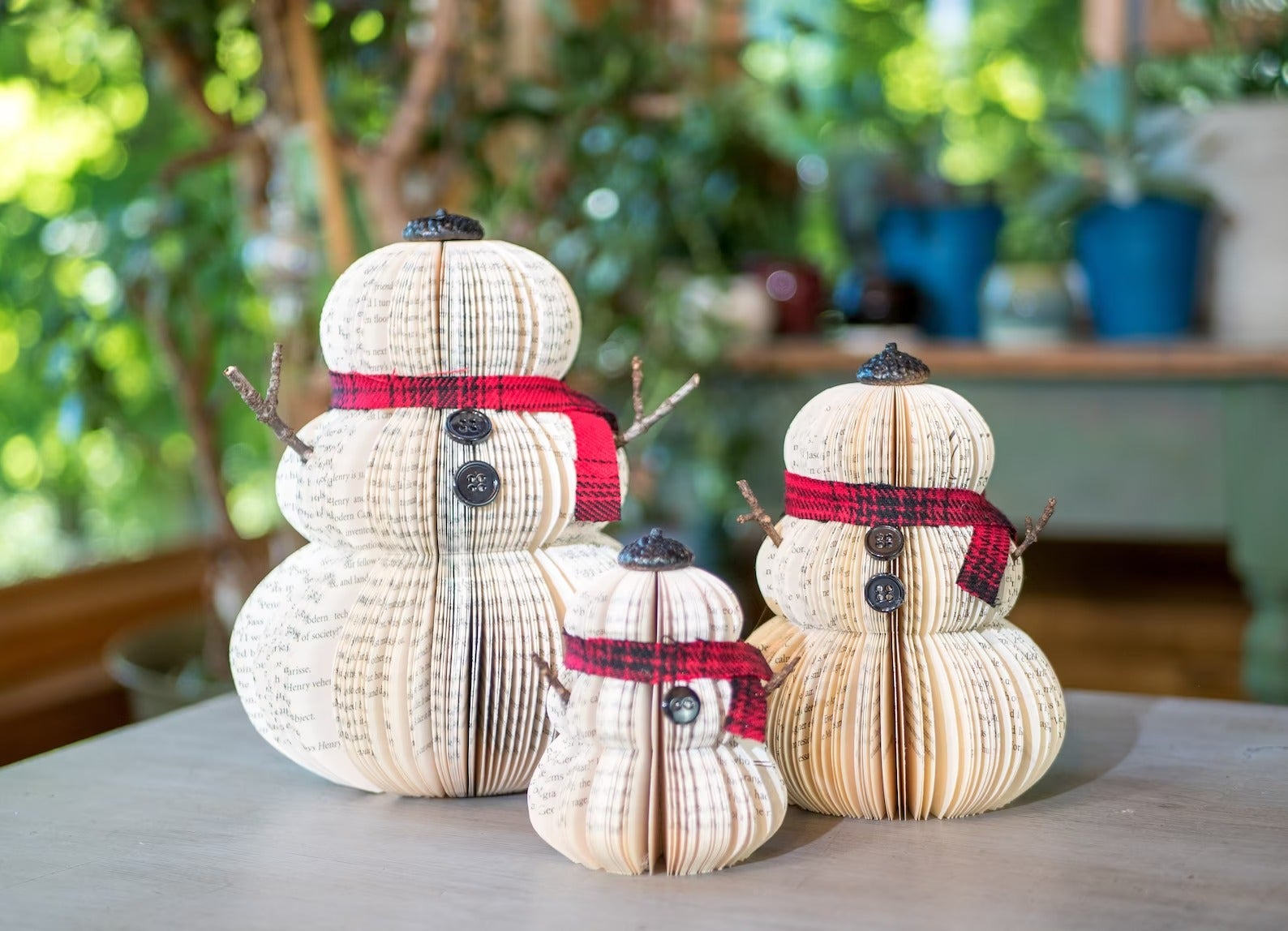 three paper snowmen of different sizes on a table