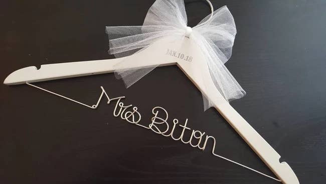 a light wood hanger with a white bow, stamped date, and a silver wire selling out 