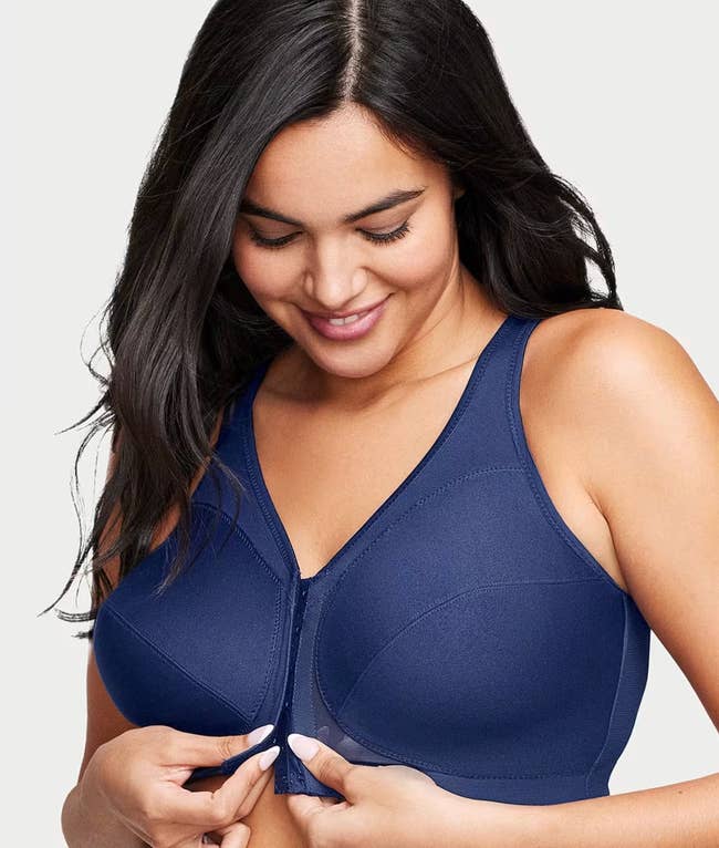 model smiling portion fastening a front-closure bra, showcasing its comfortableness and functionality