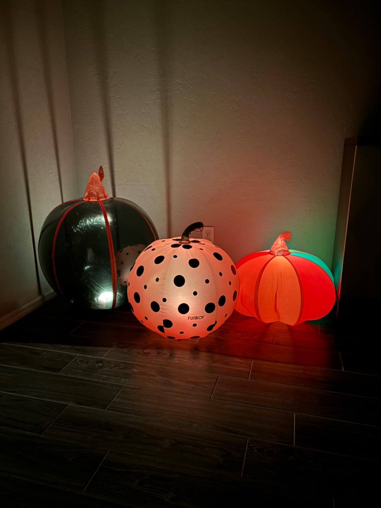 Three inflatable Halloween pumpkins with varying patterns and sizes are illuminated successful  a acheronian  corner, suitable for festive location  decor