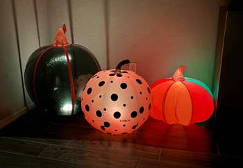 Three inflatable Halloween pumpkins with varying patterns and sizes are illuminated successful a acheronian corner, suitable for festive location decor