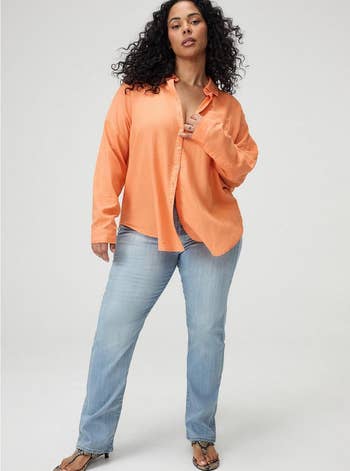 Model successful  relaxed-fit orangish  button-up garment  and airy  denim jeans, hands successful  pockets, posing confidently