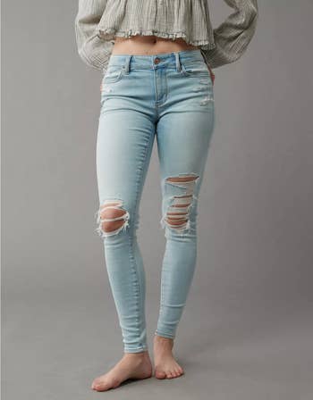 Model in distressed, light-wash skinny jeans and a cropped, long-sleeve top
