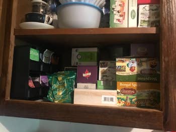 jumbled kitchen cabinet with boxes of tea bags