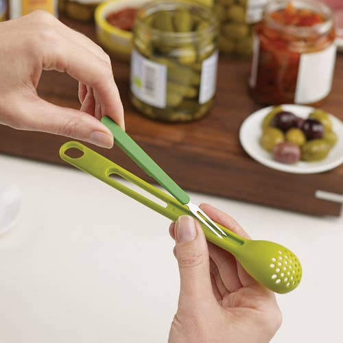 hand holding slim green strainer spoon with two-prong fork in the handle 