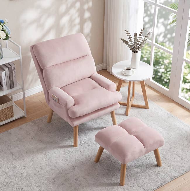 Plush armchair and matching footstool successful a cozy country mounting with a tiny circular table, books, and potted plants