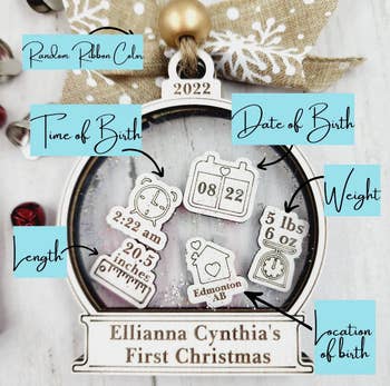 a wooden ornament shaped like a snow globe with tiny charms inside featuring details about a baby