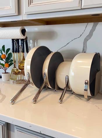 Kitchen counter with a metal rack holding four pots upright for easy storage