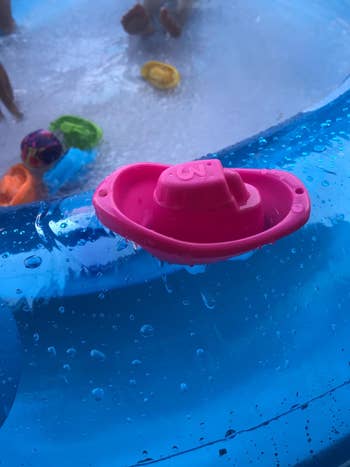 a pink plastic boat floating in a pool