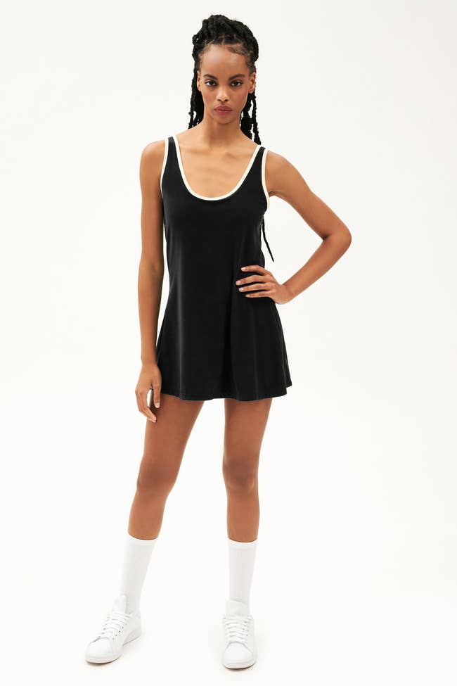 a model in a black tennis dress with white detailing around the top
