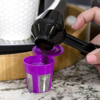 the scooper pouring coffee grounds into a reusable K-cup pod