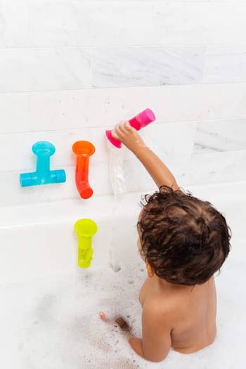 A child pouring water through one of the tubes attached to the walls