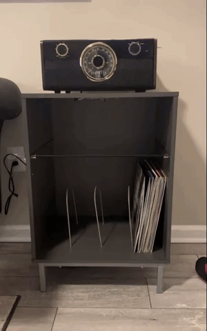 Reviewer video of wooden record player stand with a glass shelf and vinyl separator, and LED lights changing