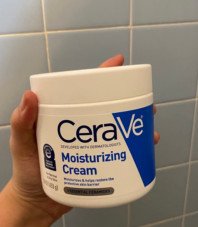 reviewer holding a jar of moisturizer