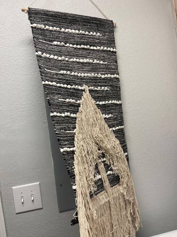 same reviewer lifting the tapestry to show how it conceals the electrical panel