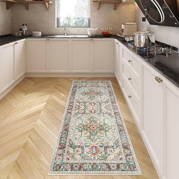 Kitchen with a decorative runner rug connected  woody  floor, achromatic  cabinets, and modern   appliances