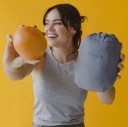 model holding up a grapefruit and the blanket pouch for scale