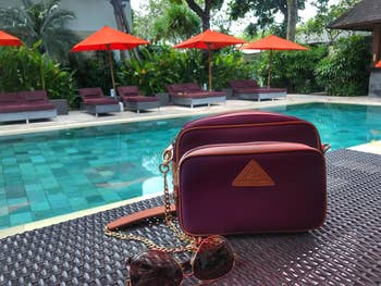 A stylish purses beside sunglasses on a poolside table, ready for a luxury outing