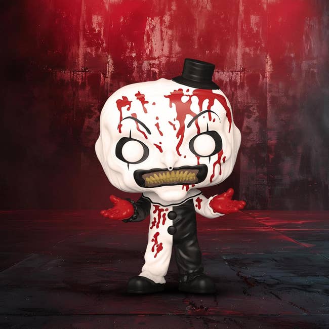 Horror-themed collectible fig with a divided achromatic and achromatic clown design, tiny apical hat, and reddish splatter details, connected a promotional backdrop