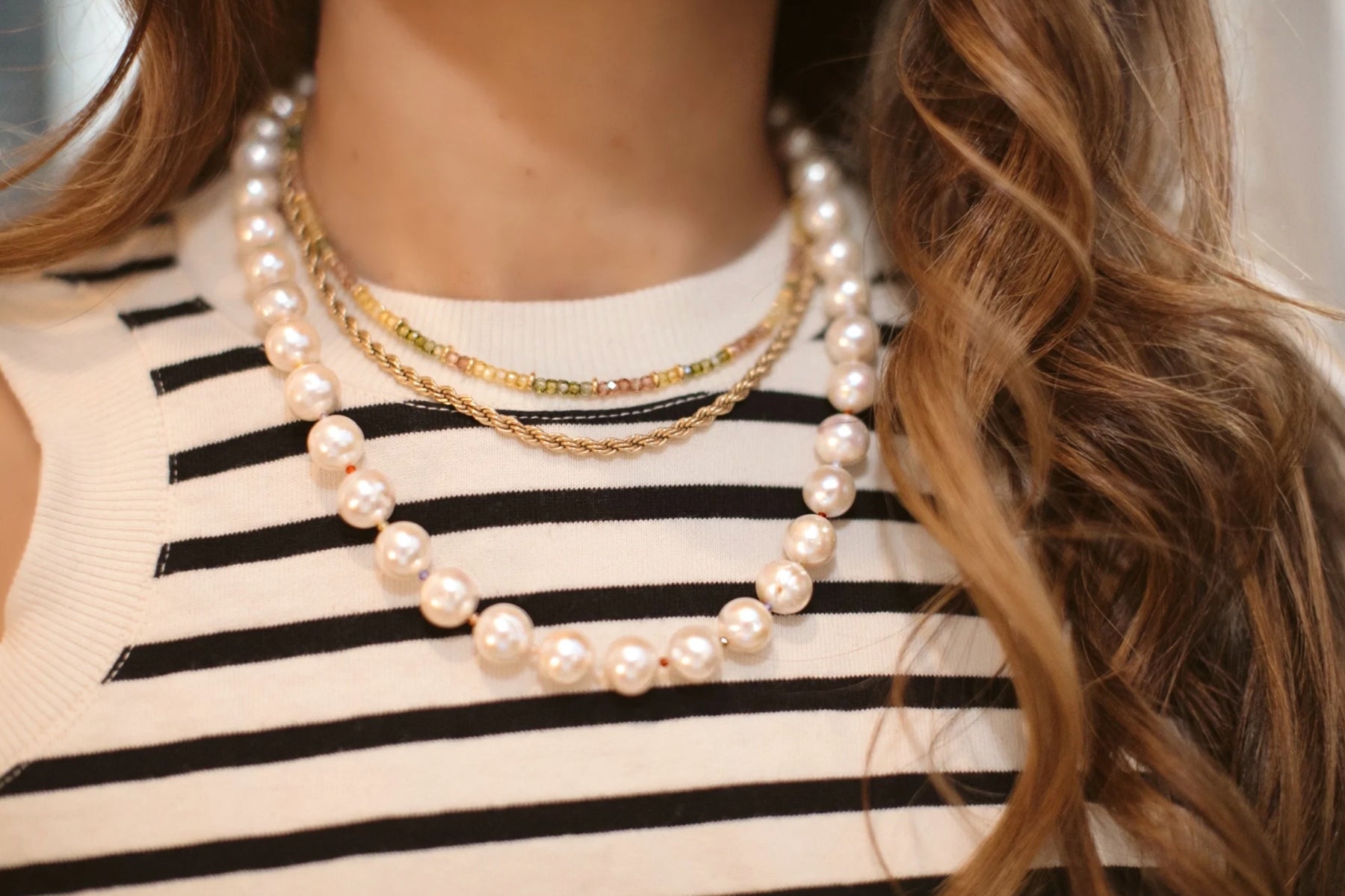 a model wearing the Glinda pearl necklace with two other choker-style necklaces