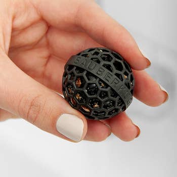 model holding the black ball filled with crumbs and debris after being used to clean the inside of a bag