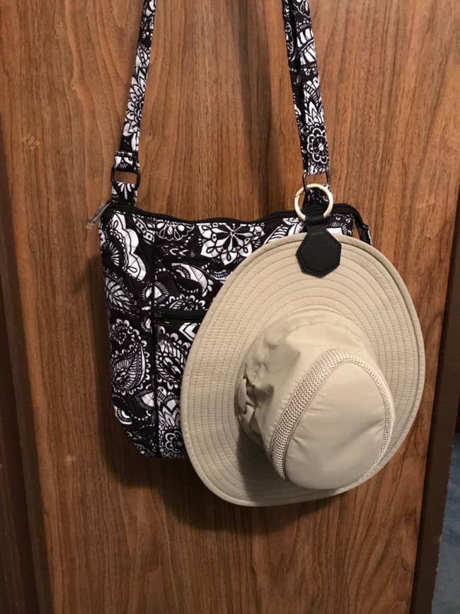 a sunhat clipped on to a bag that is hanging on a wall