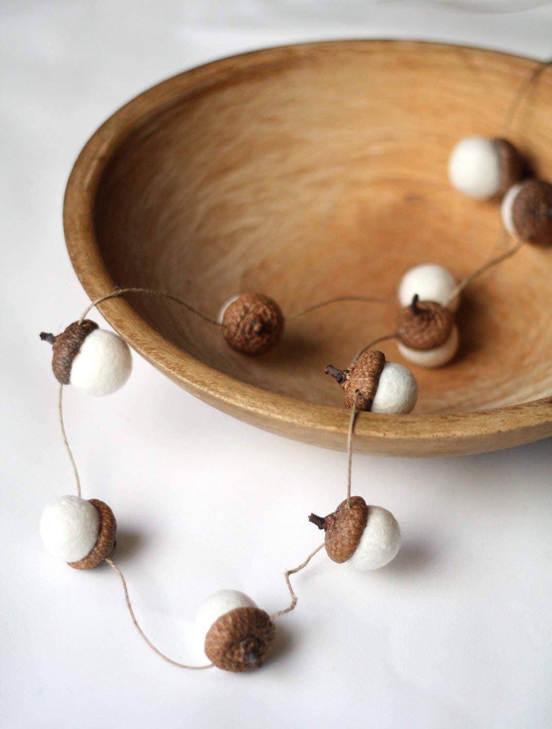 acorn tops with felted bottoms attached with thin twin. inside a bowl.