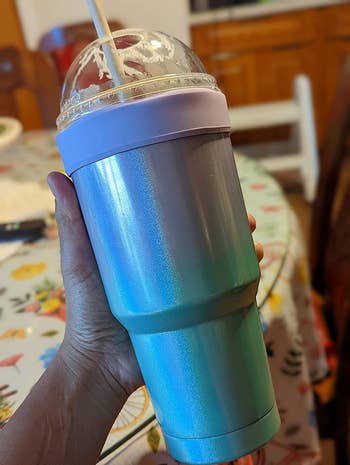 reviewer holding their coffee in the colorful reusable sleeve