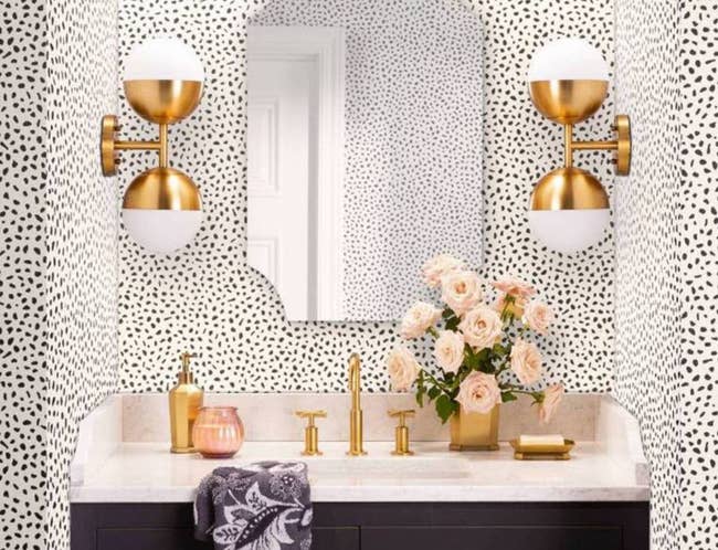 the black and white speckled wallpaper on a wall with a vanity and mirror 
