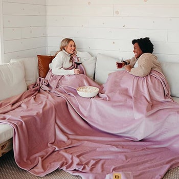 two models under the large blanket in pink