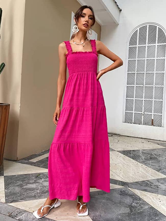 Model wearing maxi hot pink tiered dress with fitted bodice and ruffled tank top straps, paired with white flip flop heels