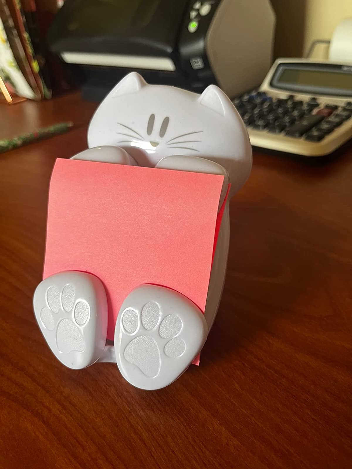 reviewer showing the cat post it note holder with pink post it notes