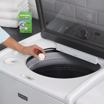 model dropping an Affresh tablet into white washing machine 