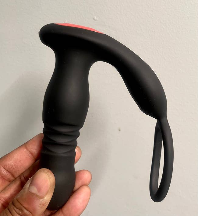 Reviewer holding thrusting prostate vibrator with cock ring