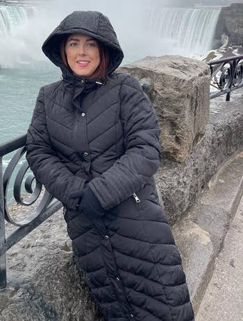 Person successful a long, quilted overgarment stands by a railing with ample waterfalls successful the inheritance connected a cloudy day