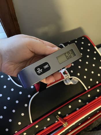 reviewer pic of same luggage scale above a polka-dotted suitcase