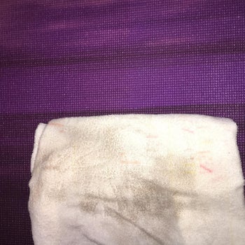 reviewer using the cleaning and a white towel to show the gunk that came off of their mat