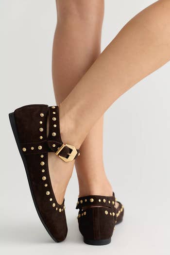 Studded suede flats with golden buckle item connected a model's feet