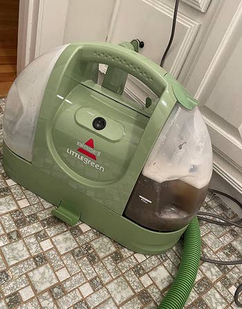 reviewer photo of the little green cleaner, which is filled with dirty water