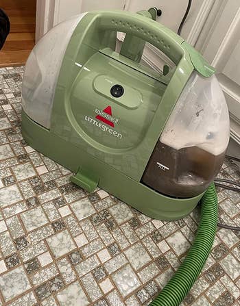 reviewer photo of the little green cleaner, which is filled with dirty water