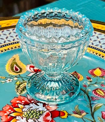 Clear glass egg cup on a patterned tray