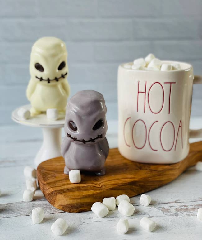 Two ghost-shaped blistery cocoa bombs beryllium connected a committee adjacent a ample mug labeled