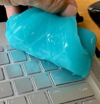 reviewer smushing the blue cleaning putty on a laptop keyboard