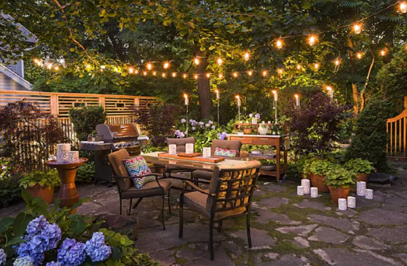 string lights hanging over patio furniture in a backyard