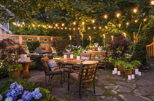 string lights hanging over patio furniture in a backyard 