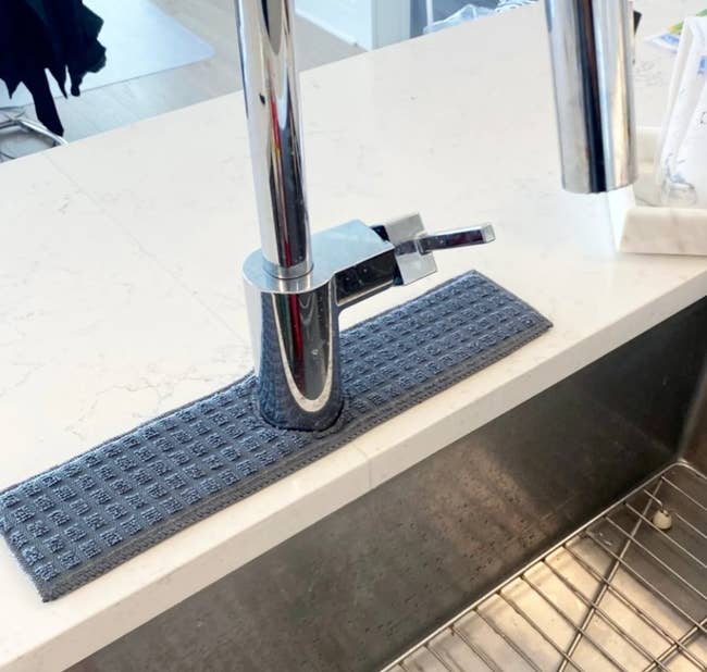 the blue splash catcher placed around a kitchen sink faucet