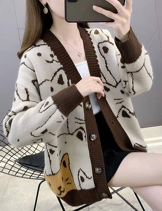 a model wearing a tan cardigan with brown trim and a cat pattern 
