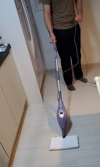 Reviewer using purple steam mop on white floor