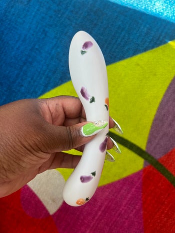 Hand holding porcelain dildo decorated with eggplants and peaches